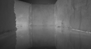 A black and white image of walls surrounding a glassy surface.
