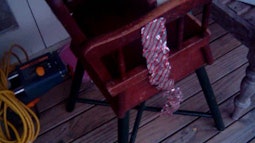 A view down onto a child's high-chair with a silver and red plastic ribbon on it.