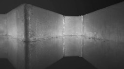 A block of ice on a reflective surface is illuminated from behind.