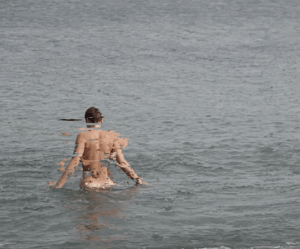 A naked body glitches whilst entering a grey sea