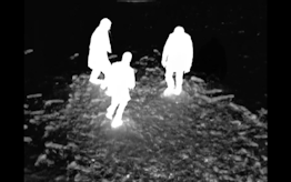 An inverted image shows three bright white figures moving about on a dark black landscapes