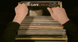 Two hands look flick a selection of records in a box