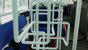 The interior of a bus or tram that is filled with a white tube that loops around to form an overlapping knot. The tube is similar in appearance to the bus's safety rail.