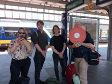 Four people stand smiling at a train station in Germany
