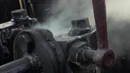 Steam plumbs out from an old engine made from steel.