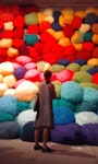 A woman standing in front of a pile of colourful puffy balls.