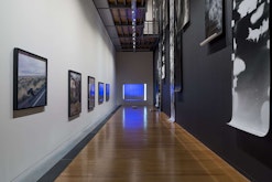 A long hallway-like gallery has framed images and long photographs displayed