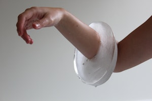 An arm witheringly supports a bracelet made of ice which is shedding drips from it's weighty body