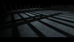 Shadows from a jail cells bars on a concrete ground.