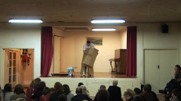 A person stands on stage making an outfit out of cardboard boxes.