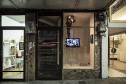 A small gallery in between a laundromat and a homeware store is displaying golden poetry as on the glass and a video work by Cushla Donaldson