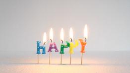 Flaming letter candles spell out the word “Happy”, as the candles burn the word is melting with the heat of the flame creating a melancholy feel