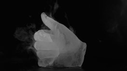 A hand made of ice gives the thumbs up. Vaporous icy mist arises from the hand