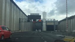 The view from the front seat of a car as it drives towards a large urban tunnel.