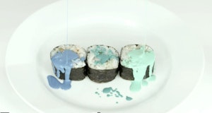 Three sushi rolls on a plate are drizzled with green and blue paint