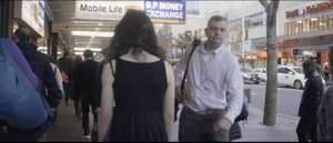 A woman walks along a busy street as city workers walk by