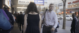 A woman walks along a busy street as city workers walk by