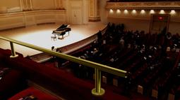 A digitally imposed stainless steel bar runs along the balcony seating in a concert hall. There is a grand piano on the stage in the background.