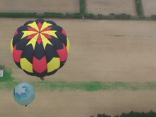 Hot air balloons rise over bare fields