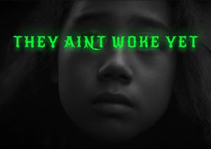 The text 'They Aint Woke Yet' in neon green is digitally imposed across the eyes of a young Māori child.