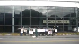 A group of people hold signs outside the Amora hotel.