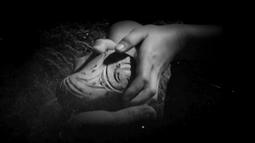 Two shadowy hands hold a Māori carving.