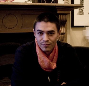 A person sitting in a chair with a orange scarf tied around their neck.