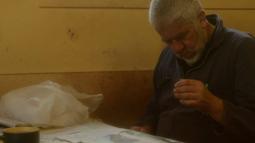 A man sits at a table reading a newspaper.