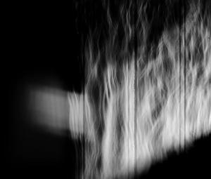 Dappled light streams through very old glass onto white walls, streams of light filter through the glass flickering on the wall like the veins of a river