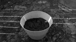 A white bucket with a sheet soaking in dye.