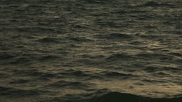 The sea at dusk, small caps appear on the waves.