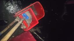 A handheld view of someone mopping a black floor, the bucket is bright red.