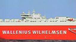 A bright red transport ship sails past, the name Wallenius Wilhelmsen is written on the side of the ship.