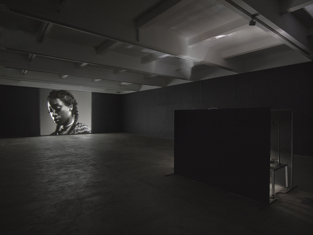 A projected black and white image of a person who looks reflective and sombre