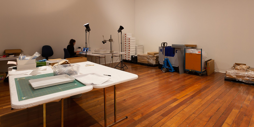 A workroom with hard wood floors, a person is working on their computer in the corner