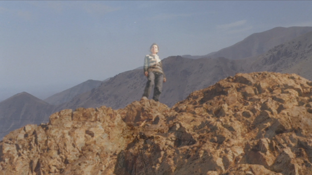 A fading image of a boy on a rocky landscape