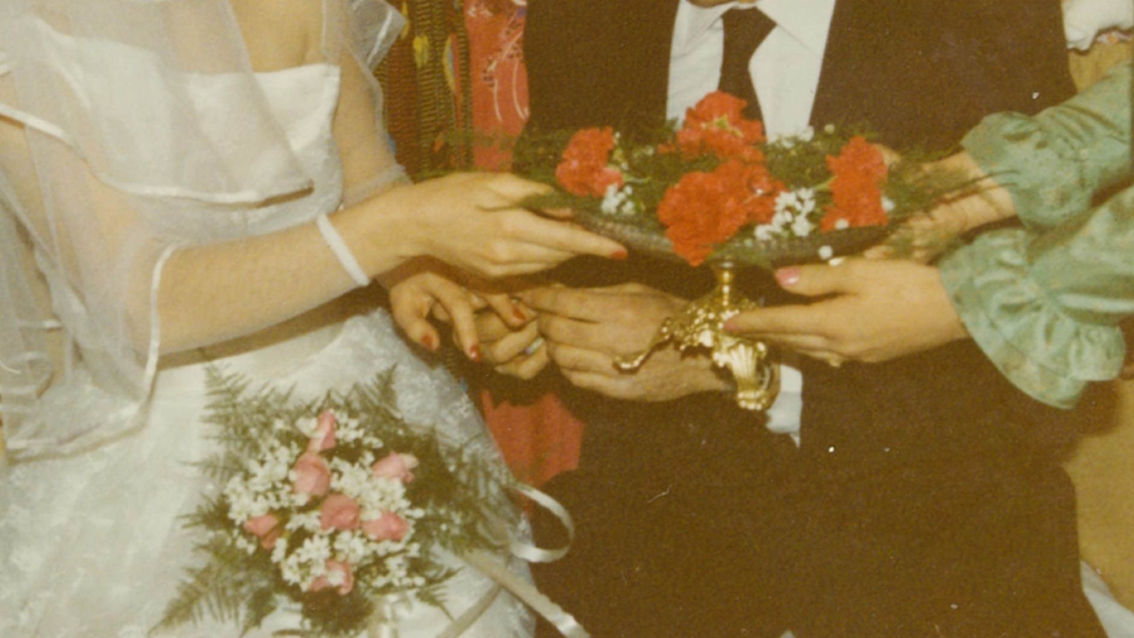 A wedding photo of people passing a silver dish filled with flowers