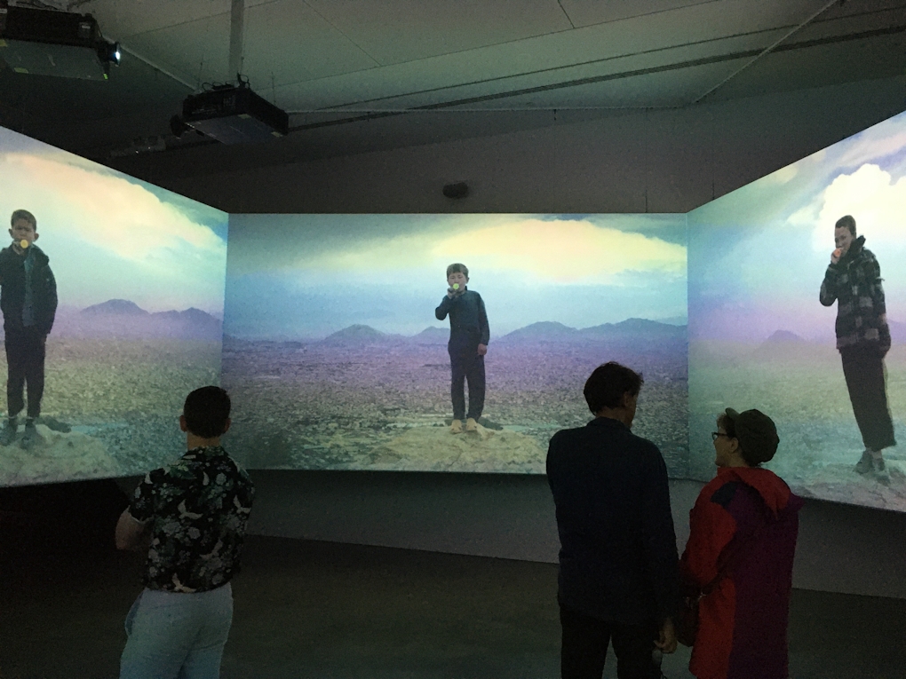 A three channel video work, each screen showing a person eating something on a dreamlike landscape