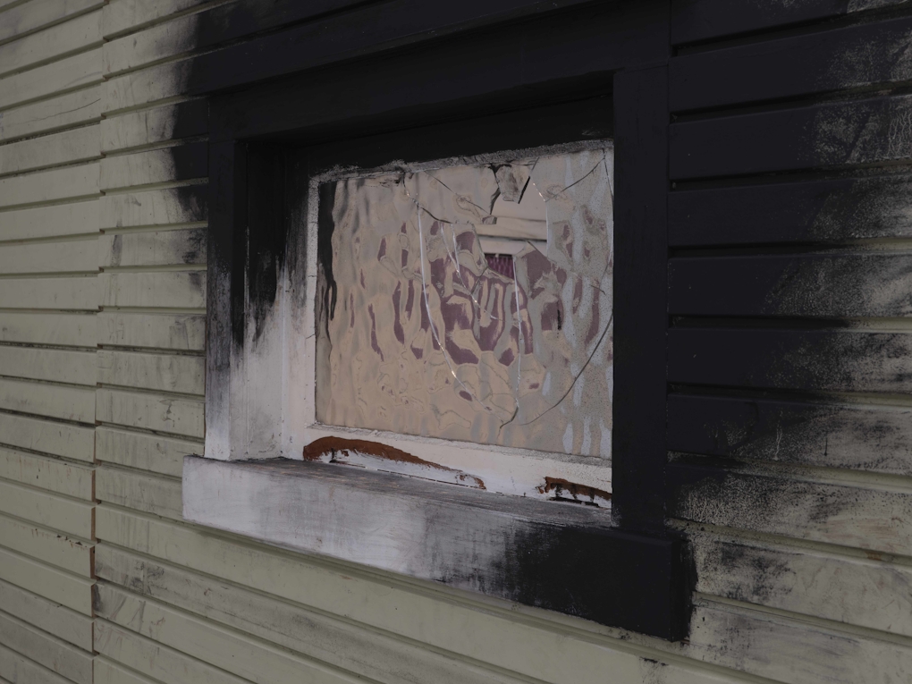 close up of a smashed window on a fire-stained house
