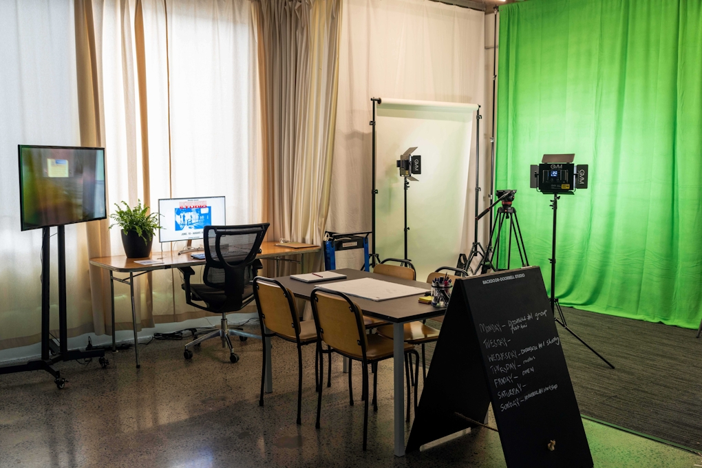 A community video making studio with green screen, lights, desk, chairs and sandwich board advertising the project