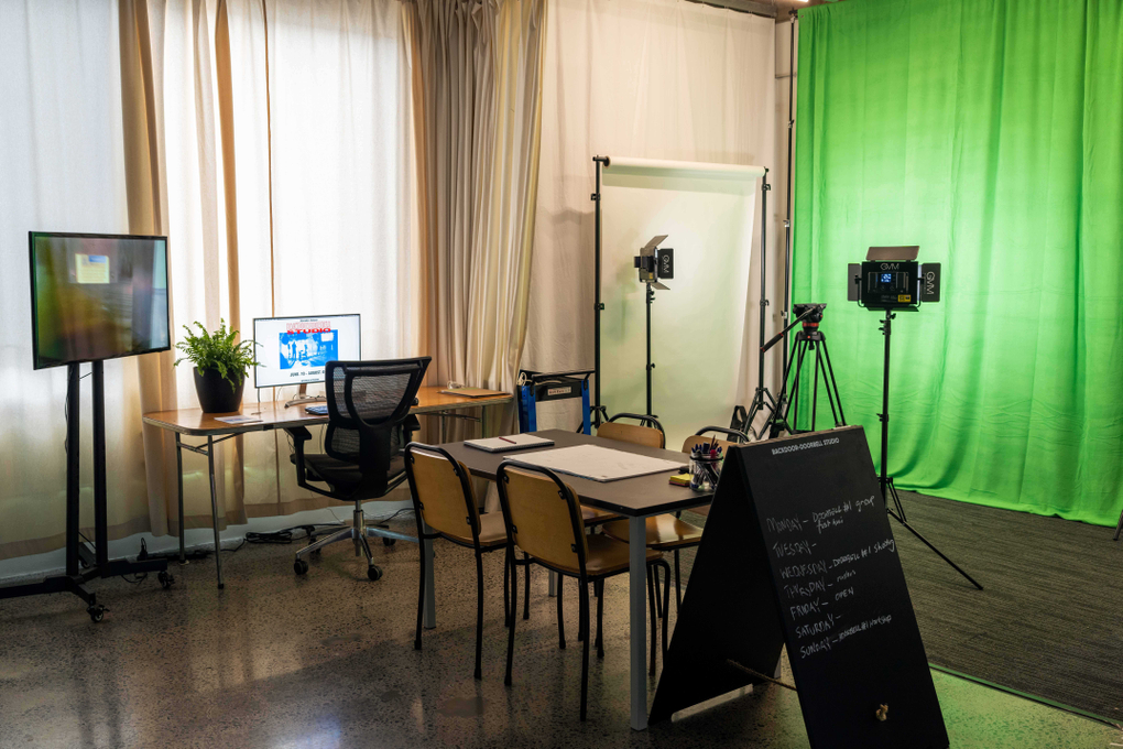 A community video making studio with green screen, lights, desk, chairs and sandwich board advertising the project