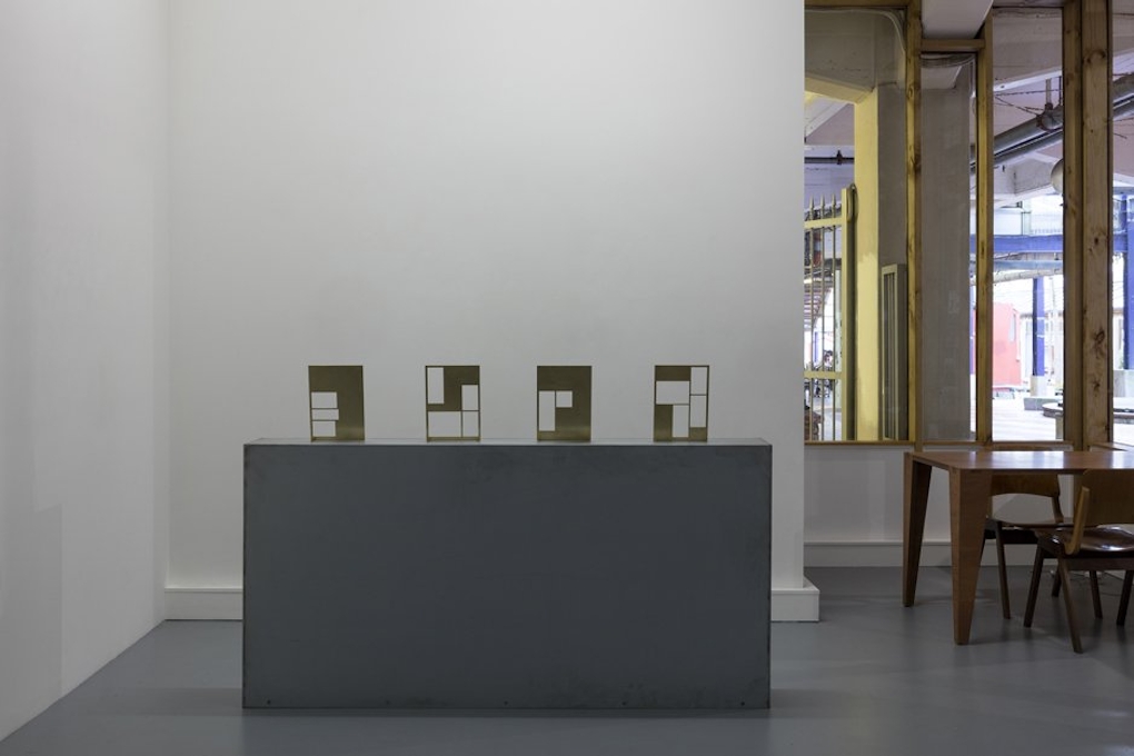 Four rectangular sculptures sit on a large plinth, each sculpture has sections missing, intimating columns in a newspaper.