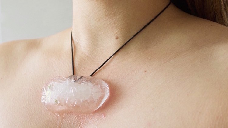 An medallion made of ice melts slowly against a persons neck, leaving a slight red mark underneath