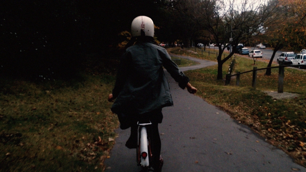 Someone happily rides their bike through a darkening park with their hands off the wheel