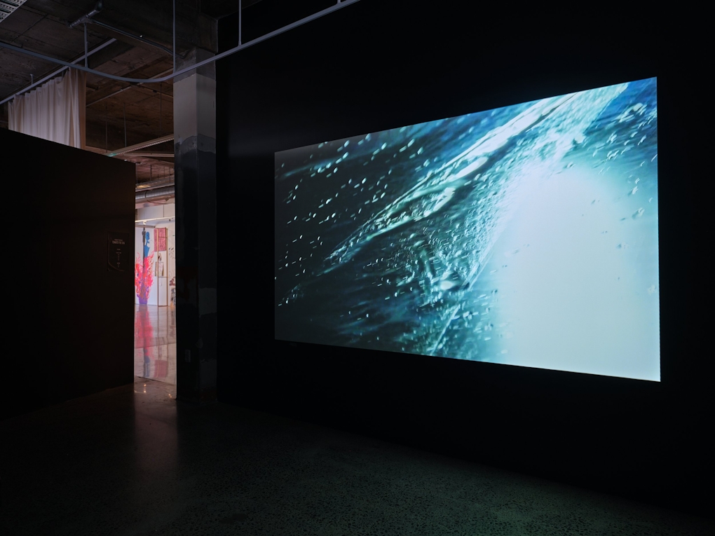 A big screen in a darkened room that shows a watery bubbly surface.