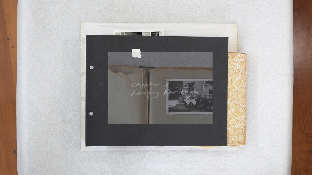 A birds-eye view of a domestic photo album, containing black and white images of people and interiors
