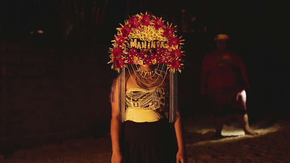A person wear one of Sione Monu's signature beaded headdresses at night