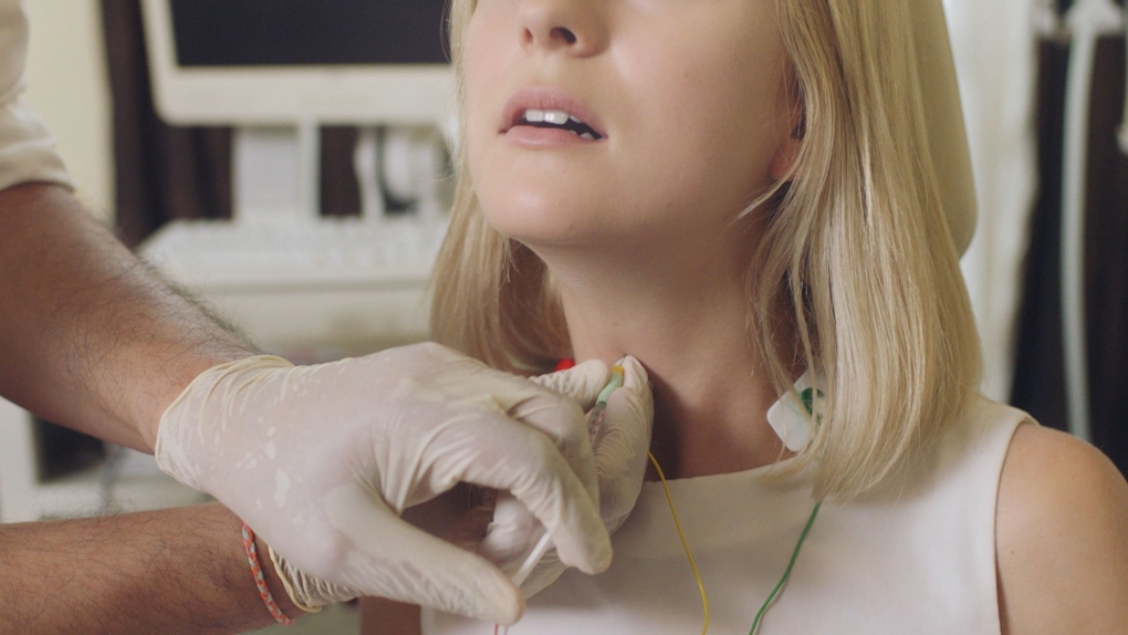 A women's throat is about to be injected with a needle by someone wearing rubber gloves.
