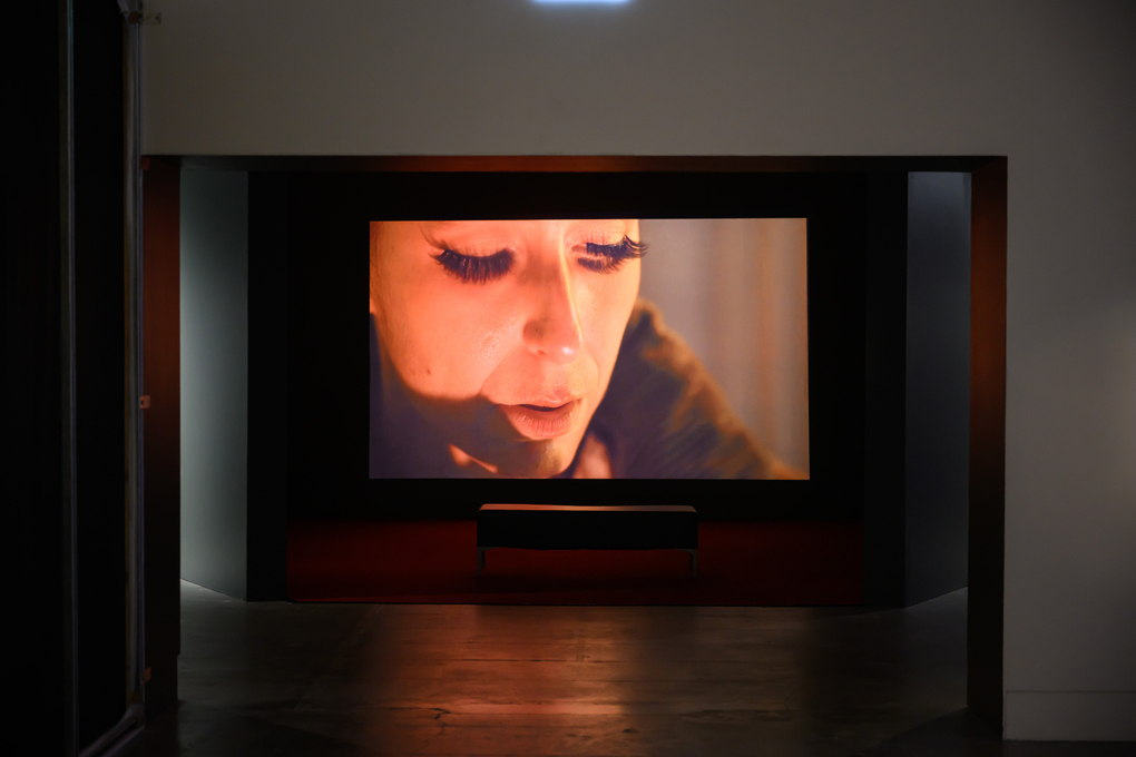 A screen shows a close up of a woman's face with exaggerated false eyelashes