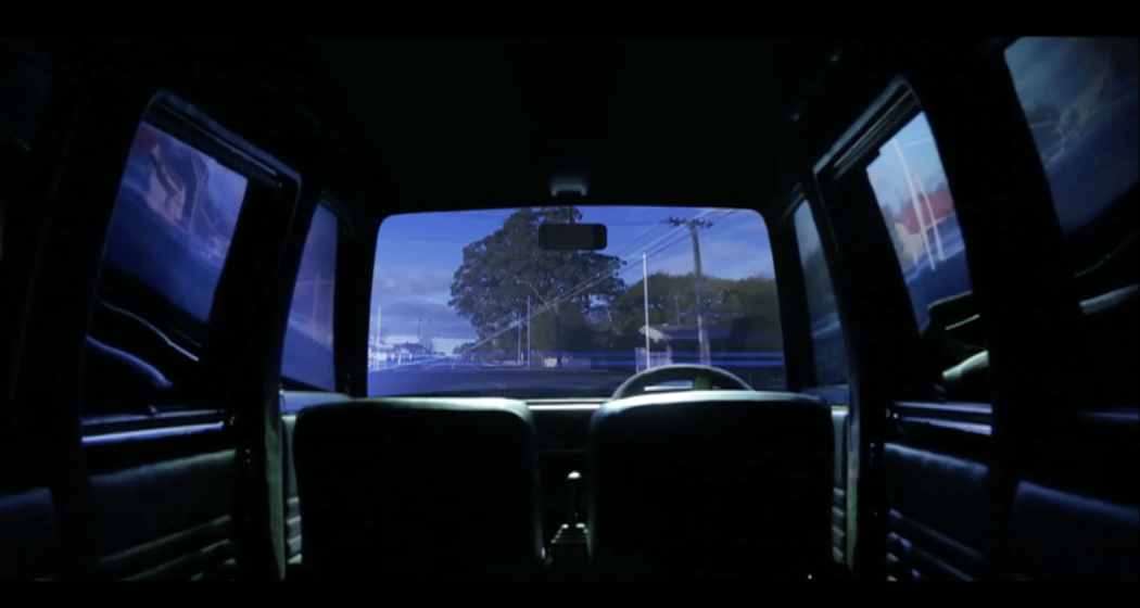 A view from inside a car looking outwards through the windscreen to see a tree and power-pole